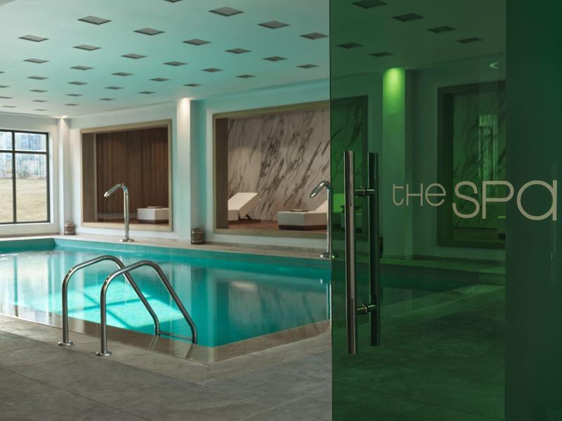 Interior de una piscina cubierta moderna con pared de mármol y entrada al spa