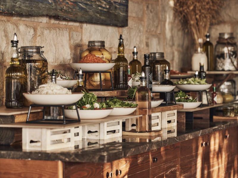 Buffet rústico con varios platos y frascos decorativos sobre mesas de madera.