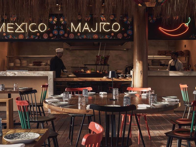 Interior de un restaurante mexicano con decoración rústica de madera y mesas preparadas.