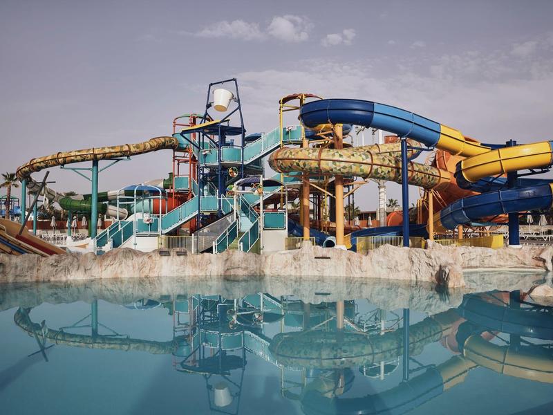 Parque acuático con toboganes sobre una piscina bajo un cielo nublado.