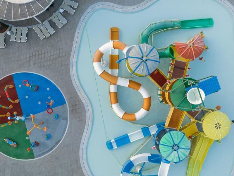 Vista general de un parque acuático con varios toboganes y una piscina para salpicaduras.