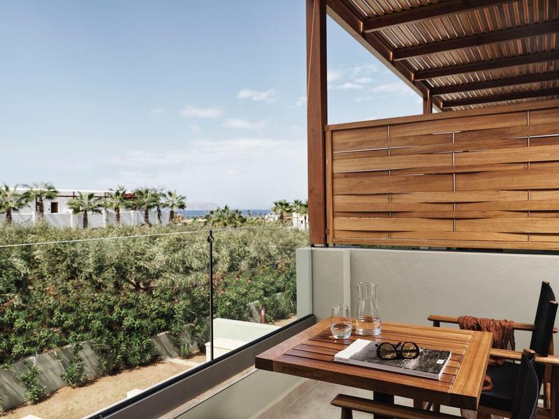 Terraza de madera con mesa y sillas con vistas al jardín y paisaje lejano.