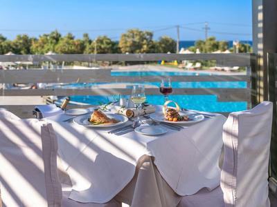 Terrasse mit gedecktem Tisch, Pool im Hintergrund, Holzgitter wirft Schatten, blauer Himmel.