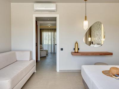 Moderner Raum mit weißen Wänden, Sofa, Bett, hängender Lampe und Wandspiegel neben Flur.