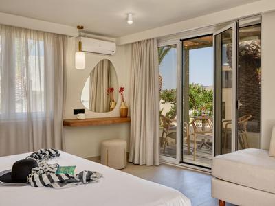 Helles Schlafzimmer mit Doppelbett, Kommode, Balkon und beige Gardinen, mit natürlichem Tageslicht.