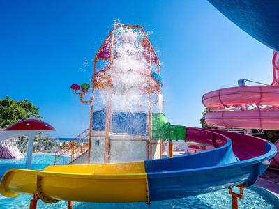 Bunte Wasserrutsche und Wasserpark mit Spritzwasser unter blauem Himmel.