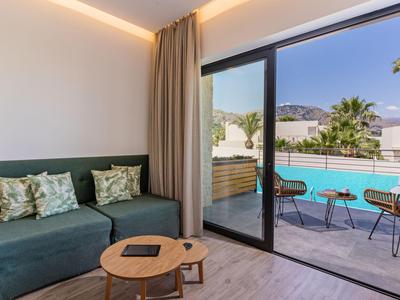 Nowoczesny pokój hotelowy z sofą, małym drewnianym stolikiem i widokiem na basen oraz taras.