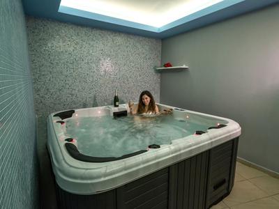 Frau entspannt in großem weißem Whirlpool mit blauer LED-Beleuchtung in modernem Raum.