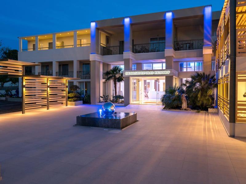 Modern hotel terrace at night lit up with plants and seating areas.