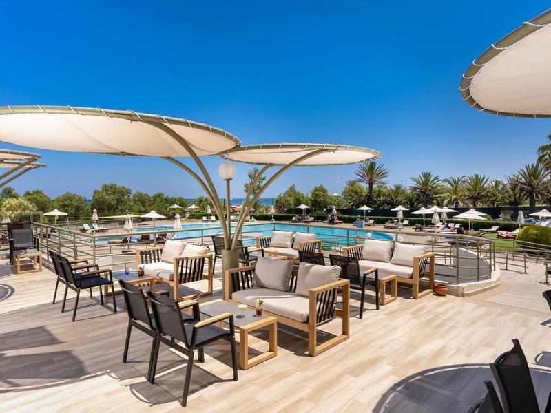 Luxurious outdoor area with pool, sunshades, and comfortable seating under clear skies.