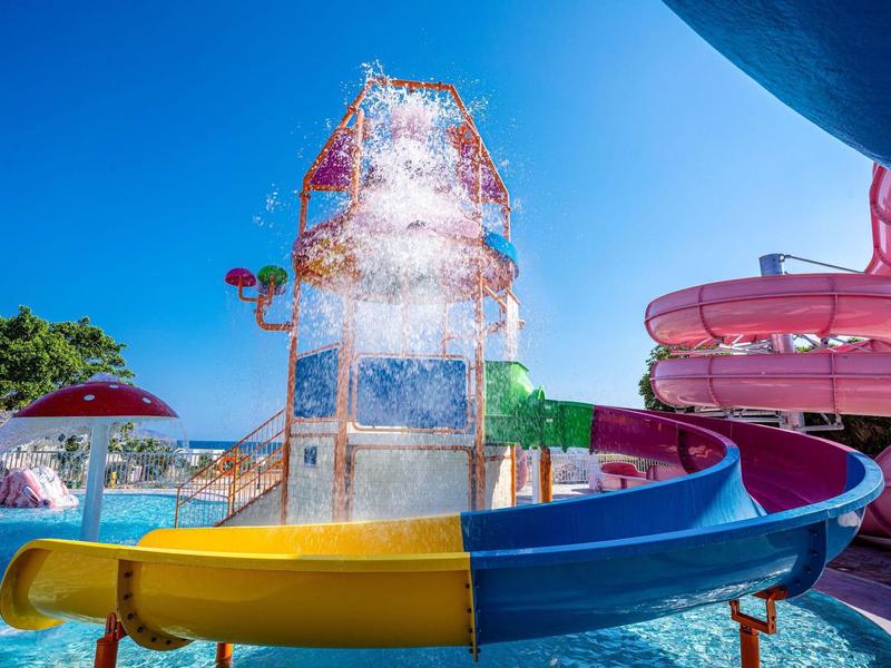 Colorful water slide and splash pad under clear blue sky at a water park.