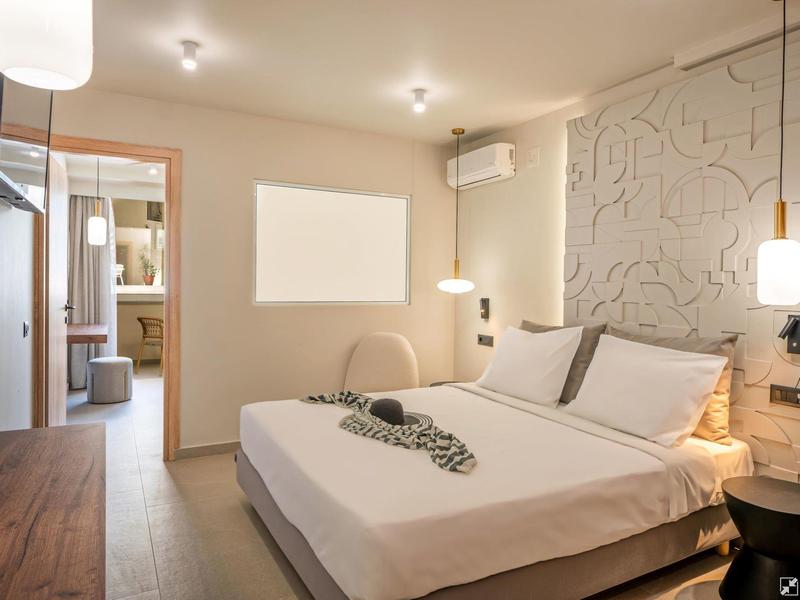 Modern hotel room with double bed, hanging lamps, and air conditioning.