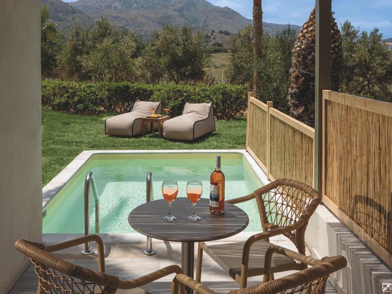 Terrace with table, chairs, and view of private pool and green landscape.