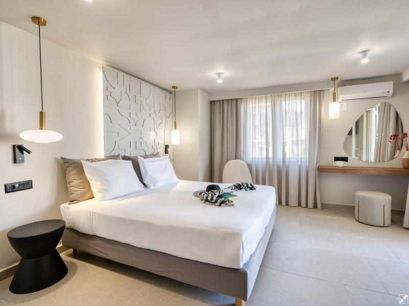 Modern hotel room with double bed, stylish desk, and large windows.