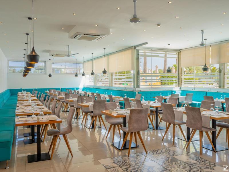 Bright, modern dining room with wooden tables and turquoise seating in a hotel.
