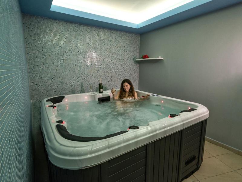 Woman relaxes in a modern hot tub in a simple room with stylish lighting.