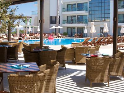 Venkovní restaurace s ratanovými židlemi a bazénem v hotelu