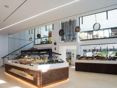 Modernes, helles Café mit großen Theken, vielen Leckereien und einer Galerie mit Geländer.