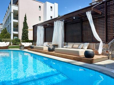 Moderní venkovní bazén s posezením a bílými závěsy v hotelu.