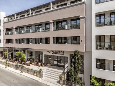 Nowoczesny budynek hotelu z wieloma balkonami i kawiarnią przy wejściu.