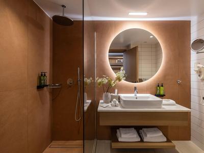 Bagno moderno in hotel con specchio rotondo illuminato e lavabo elegante.