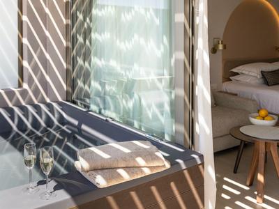 Balcone moderno dell'hotel con tendalino, ringhiera in vetro e accesso all'interno luminoso.