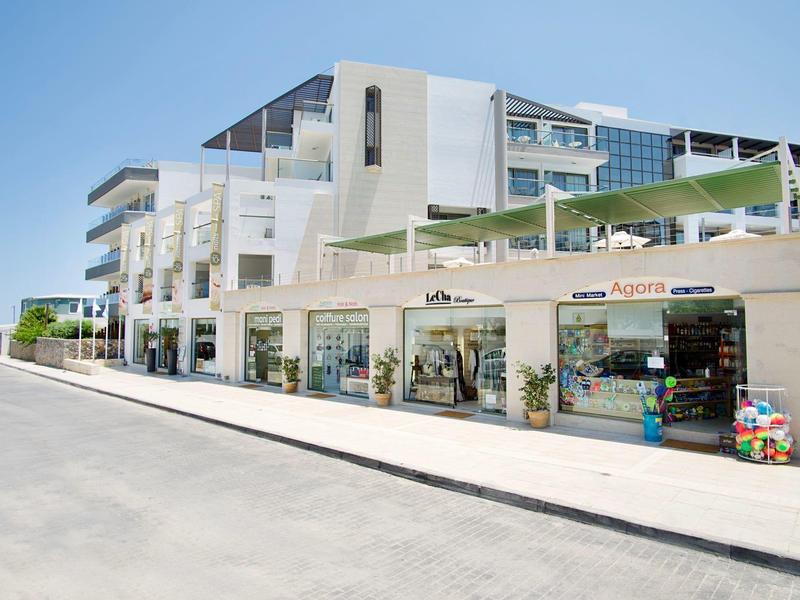 Nowoczesny budynek z sklepami na parterze i widokiem na morze pod czystym niebem.