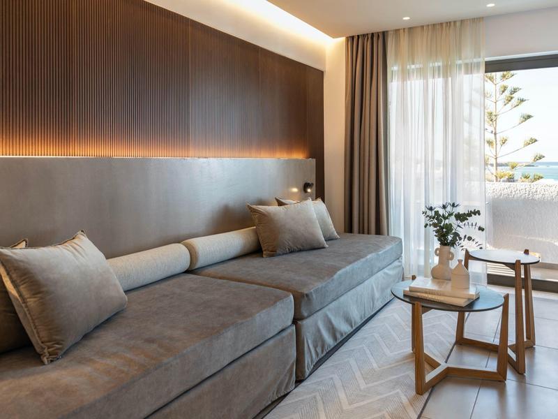 Elegancki salon hotelowy z szarą sofą i miękkim oświetleniem przy oknie.