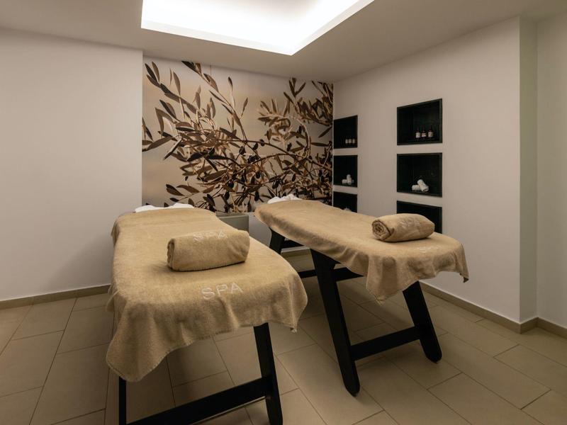 Pokój do masażu z dwoma stołami, naturalna dekoracja na ścianie, spokojna atmosfera.