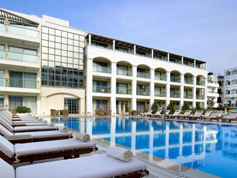 Nowoczesny basen hotelowy z leżakami i czystą niebieską wodą pod błękitnym niebem.