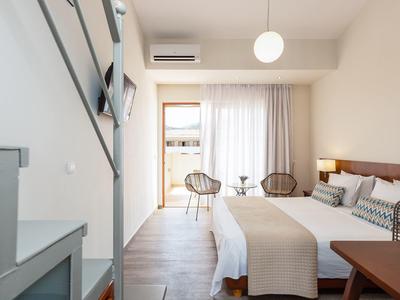 Helles Hotelzimmer mit Doppelbett, Treppe zu Galerie und Zugang zu Balkon oder Terrasse.