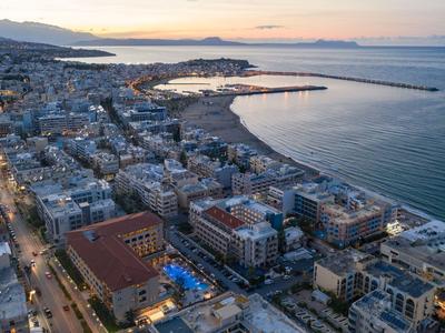 Vista de ciudad portuaria con playas, hoteles y mar tranquilo al atardecer.