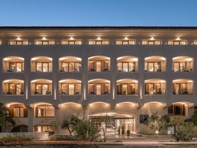 Beleuchtetes Hotel mit mehreren Balkonen und eleganter Eingangsbeleuchtung bei Dämmerung.