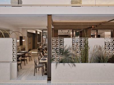 Moderner Hotel-Loungebereich mit Holztrennwänden, gepolsterten Sitzbänken und Pflanzenarrangements.