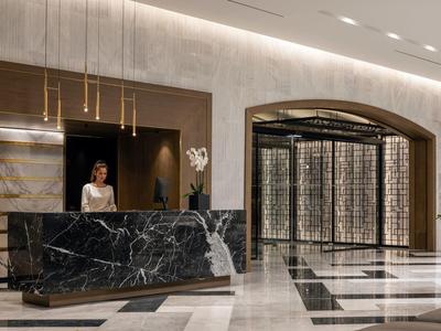 Elegante Hotellobby mit schwarzer Marmor-Rezeption und modernem Beleuchtungskonzept.