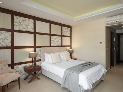 Modernes Hotelzimmer mit großem Bett, Nachttischen, Sesseln und stilvoller Wanddekoration.