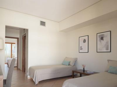 Helles Hotelzimmer mit zwei Einzelbetten, Bildern an der Wand und Holzmöbeln.
