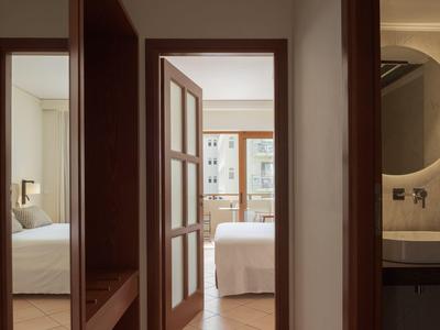 Blick durch Flur zu zwei Schlafzimmern mit Betten und Fenster in einem Hotelzimmer.