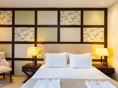 Modern eingerichtetes Hotelzimmer mit Doppelbett, Nachttischen, Lampen und Sessel.