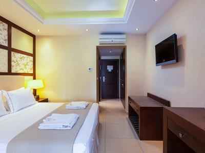 Modernes Hotelzimmer mit Bett, TV und Schreibtisch in warmen Farbtönen.