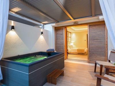 Moderner Whirlpool auf einer überdachten Terrasse eines Hotelzimmers mit Holzstühlen.