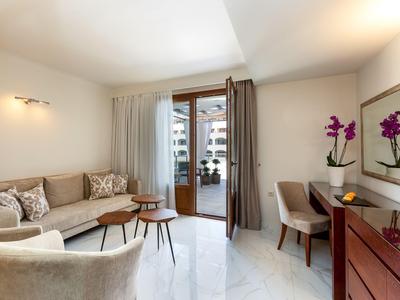 Habitación de hotel moderna con sofá, escritorio y grandes ventanas que dan al balcón.