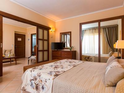 Habitación de hotel luminosa con cama doble, armario con espejos y acceso abierto a sala de estar.