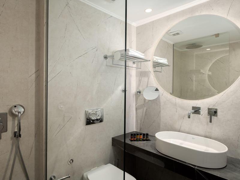 Modernes Badezimmer mit rundem Spiegel, Waschtisch und Glastrennwand