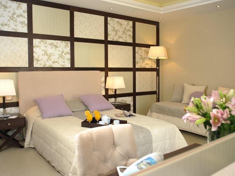 Helles Hotelzimmer mit zwei Einzelbetten, Tischlampen und einer Vase mit Blumen.