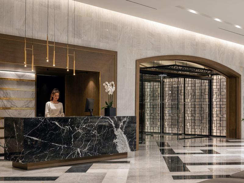 Elegante Hotellobby mit schwarzer Marmor-Rezeption und großer Weinsammlung im Hintergrund.