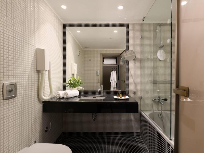 Modernes Badezimmer mit schwarzer Waschtischplatte und Glas-Duschkabine in einem Hotelzimmer.