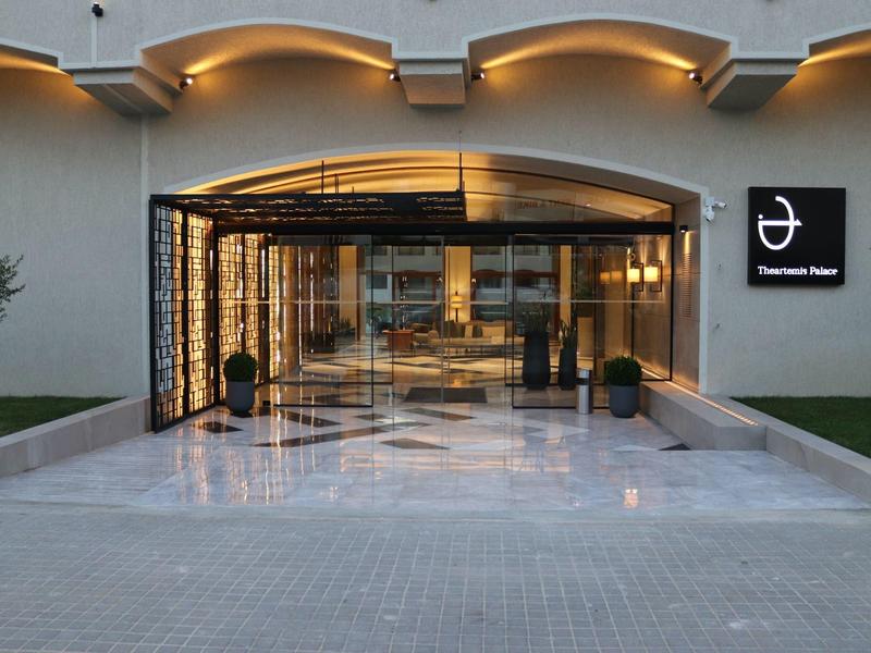 Eleganter Hoteleingang mit Glasfassade und beleuchtetem Marmorvorplatz am Abend