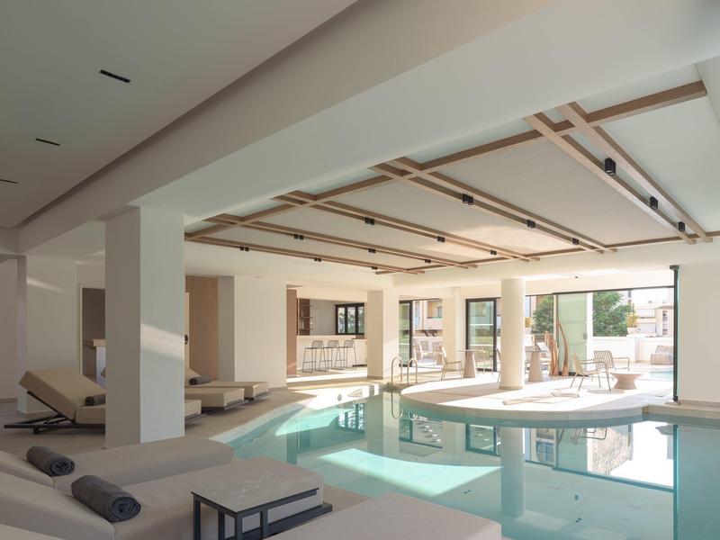 Helles Hallenbad in modernem Hotel mit großen Fenstern und komfortablen Liegen.