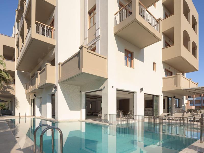 Moderner Hotelpool mit klar blauem Wasser und Balkonzimmern bei Sonnenschein.